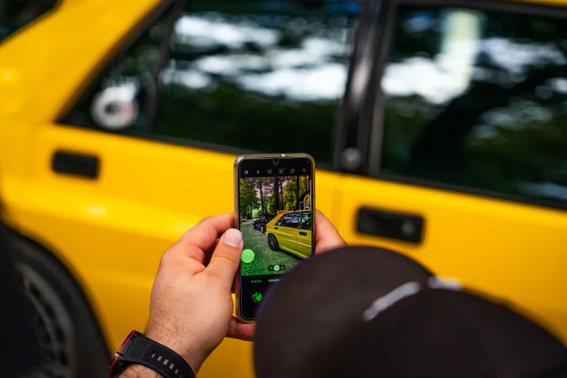Content-Aufnahme mit dem Smartphone neben einem gelben Lancia Delta